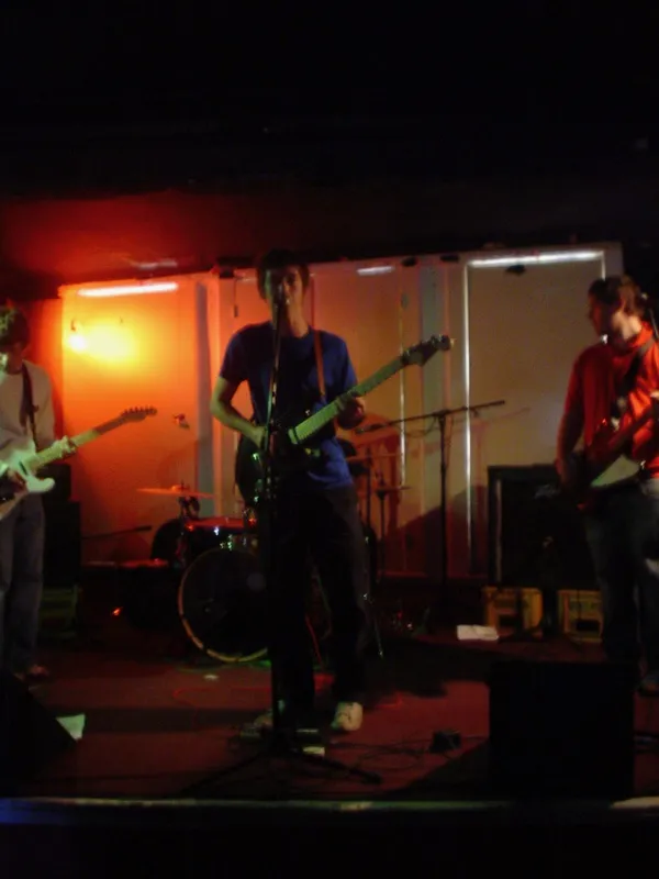 A four-piece band playing on a small stage lit in orange.
