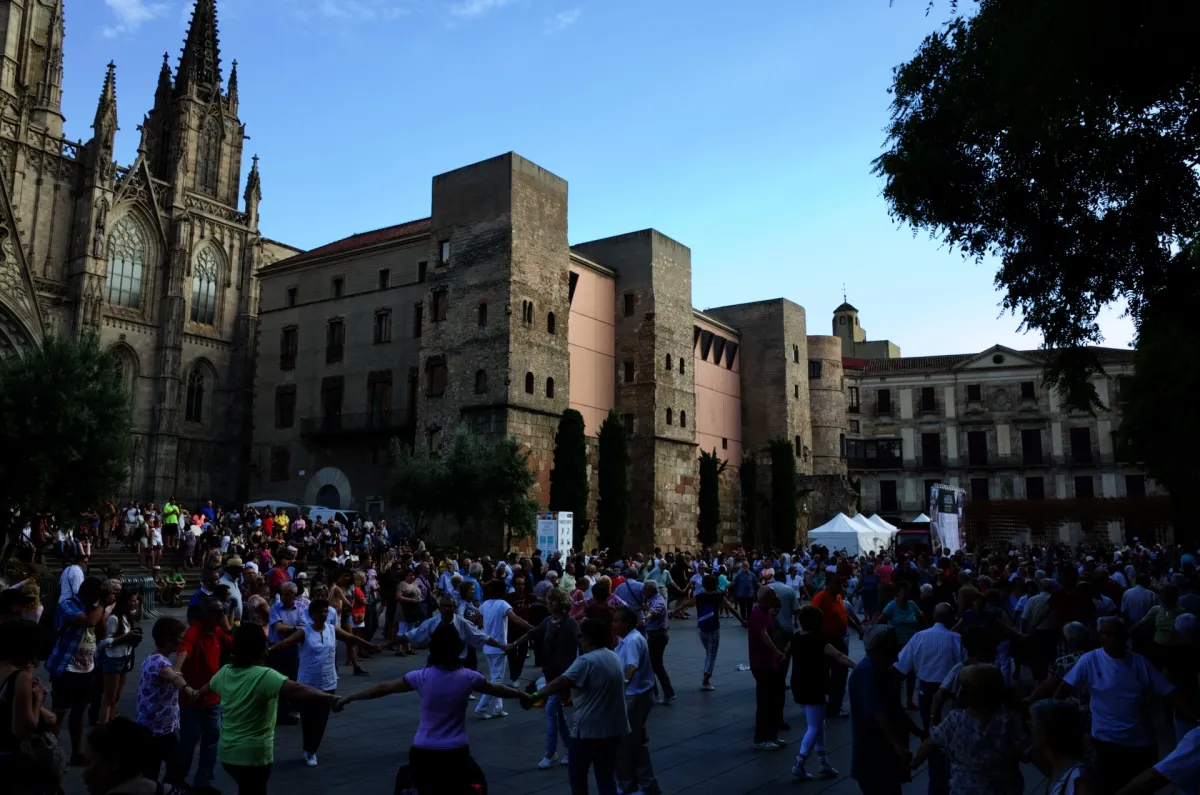 People gathered in a square below the cathedral and the old Roman wall.