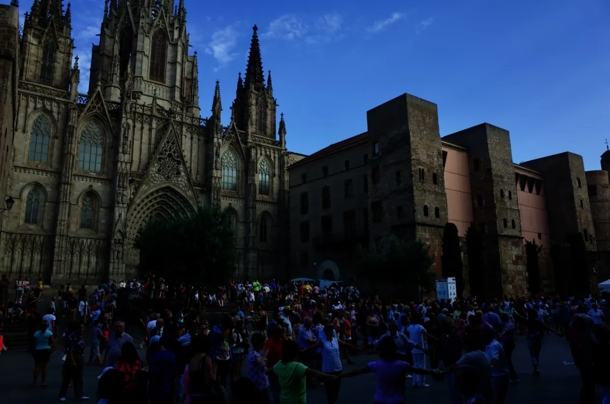 A crowd filling the square in front of Barcelona Cathedral in the evening.