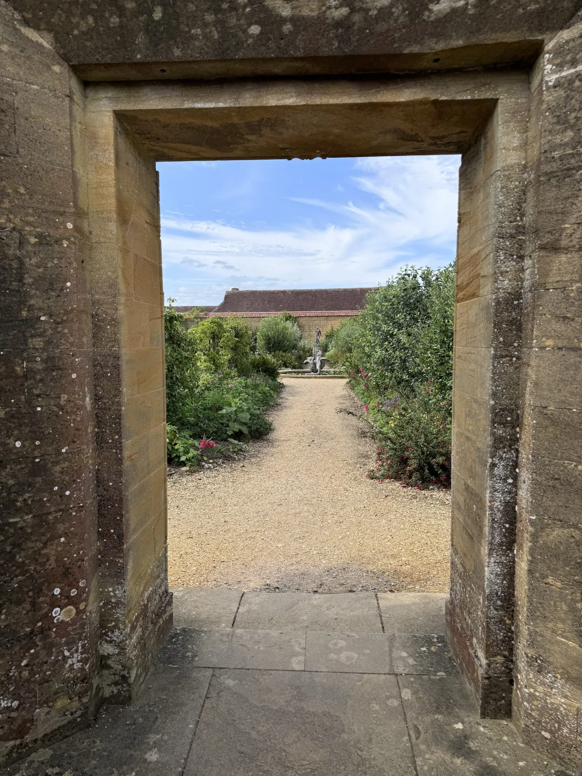 A gravel path and garden seen through a stone doorway.