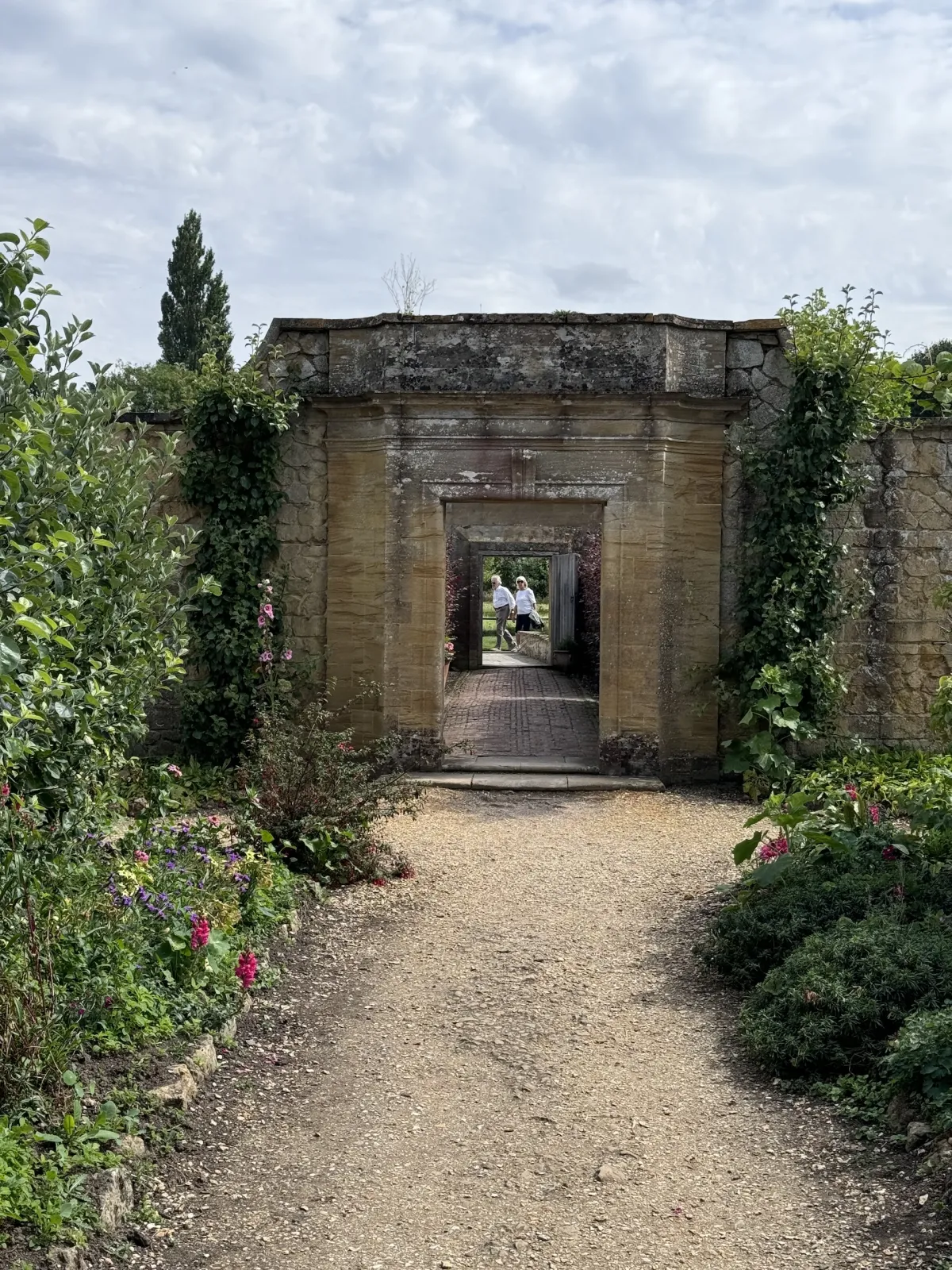 A gravel path leading to a stone gateway between garden walls.