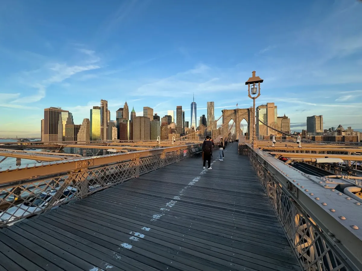 The Brooklyn Bridge walkway with the Lower Manhattan skyline beyond, including One World Trade Center.