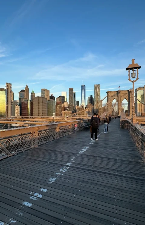 The Brooklyn Bridge walkway with the Lower Manhattan skyline beyond, including One World Trade Center.