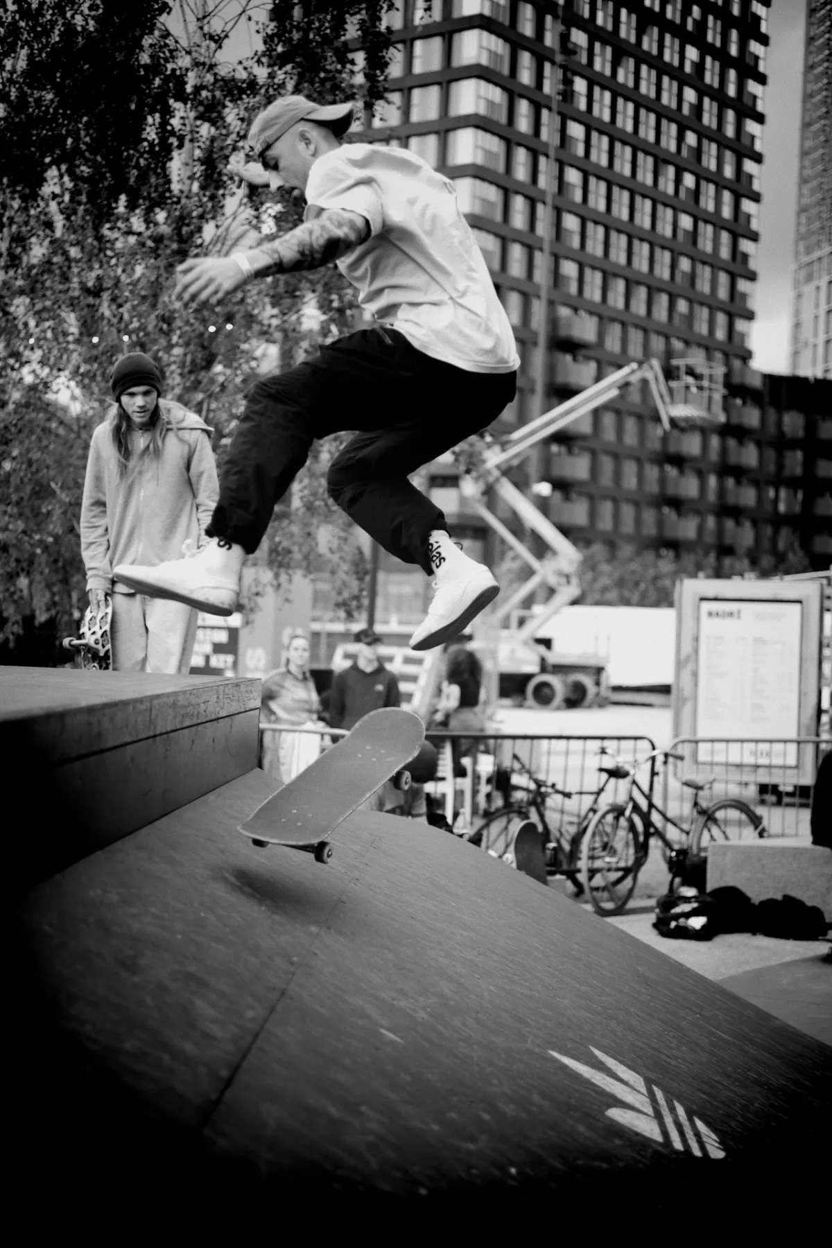 A skateboarder jumping a ramp, board separated from their feet. Black and white.