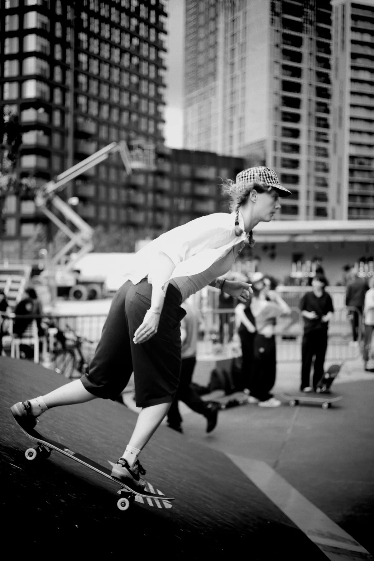 A skateboarder riding down a ramp in front of buildings under construction. Black and white.