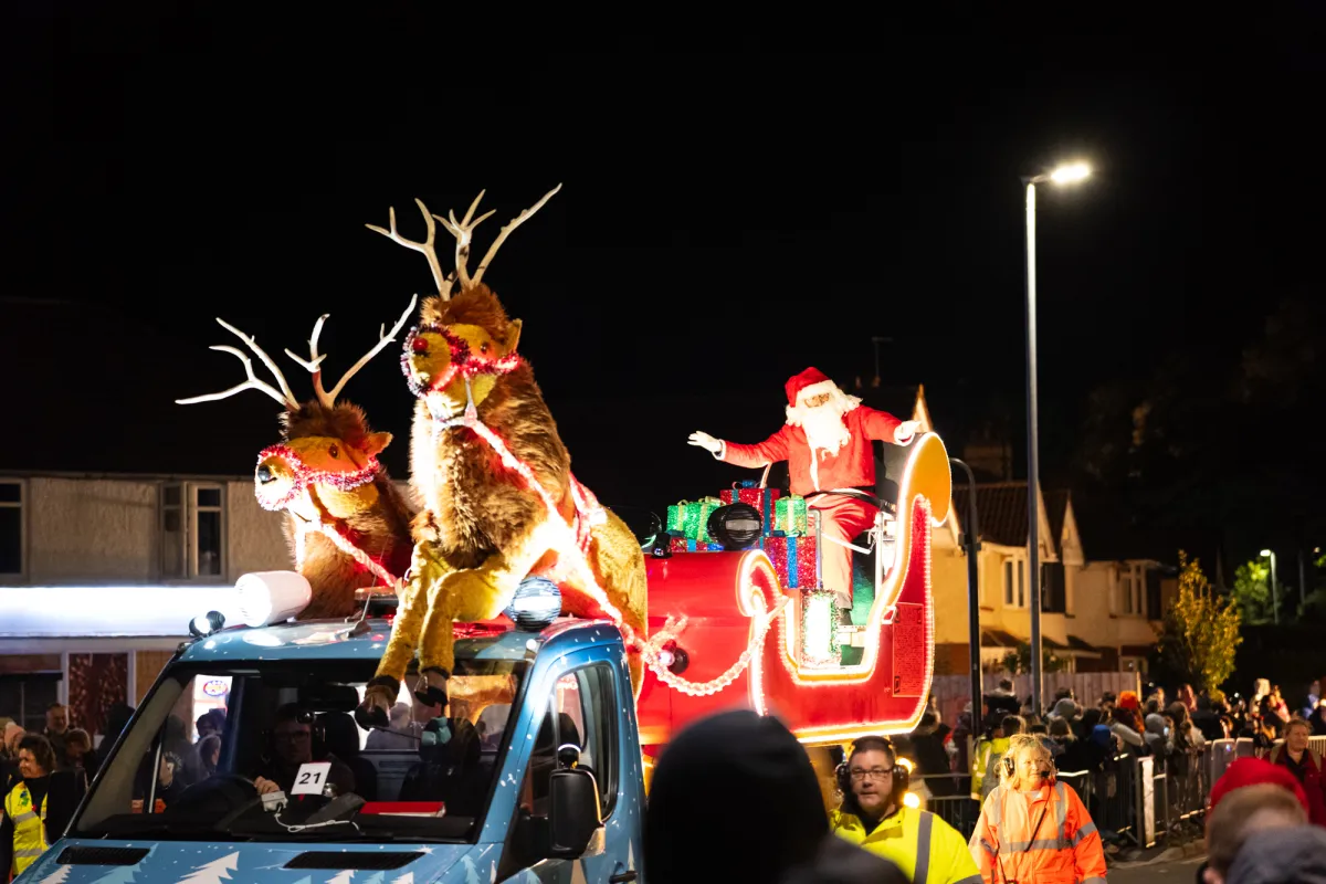 A Father Christmas figure in a sleigh pulled by model reindeer on a float.