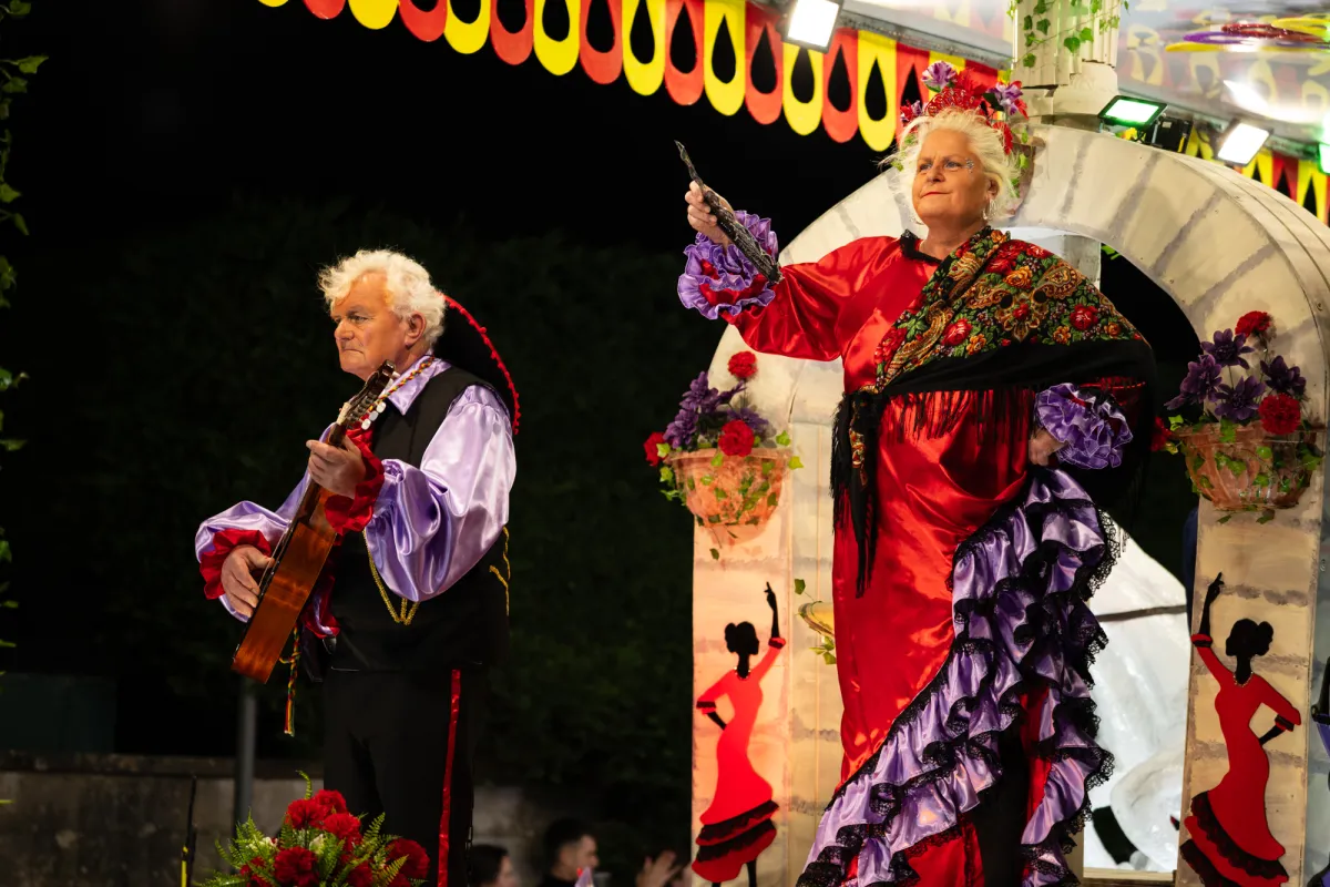 Two performers in Spanish costume on a float, one playing a guitar.