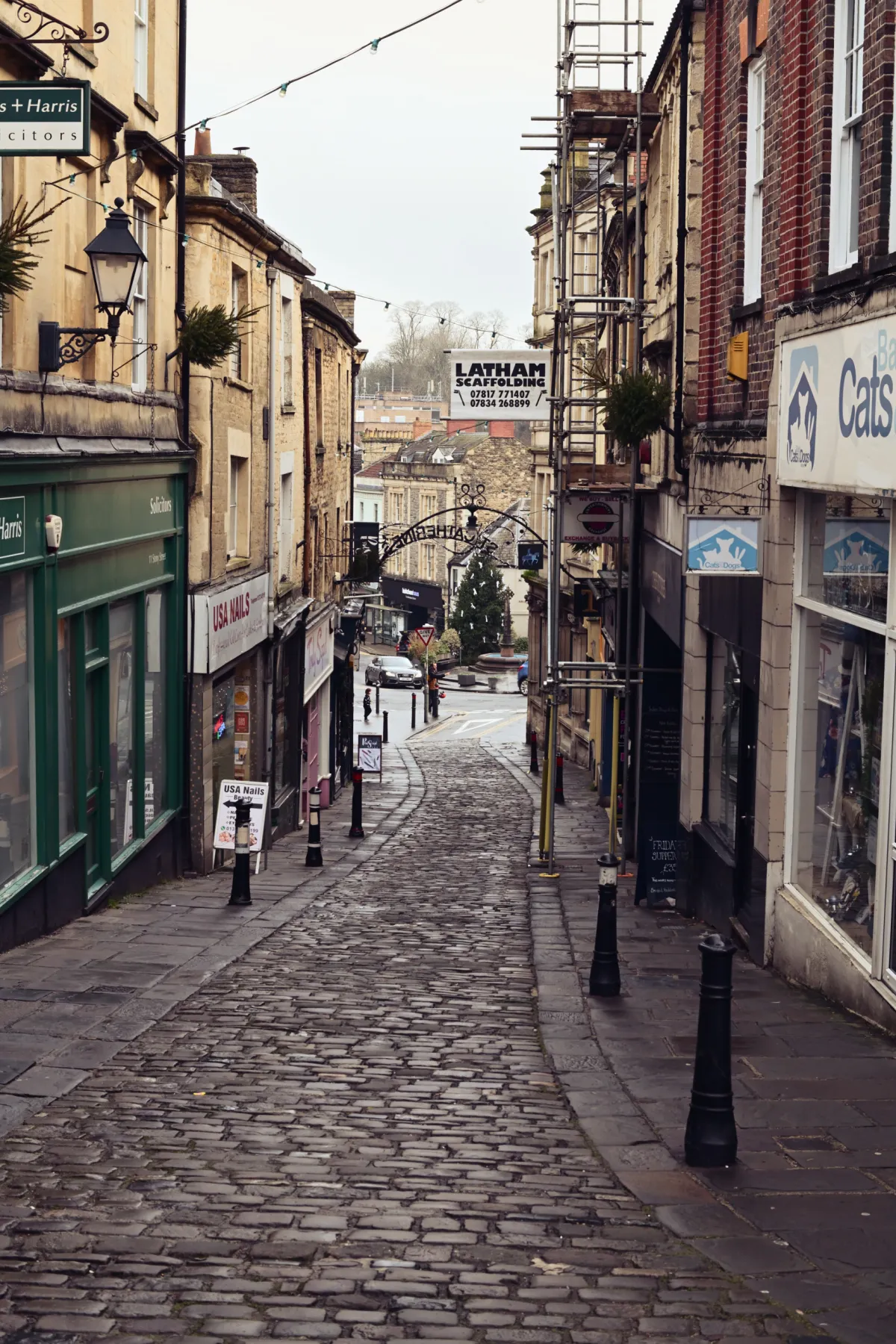 A cobbled shopping street lined with shopfronts and scaffolding.