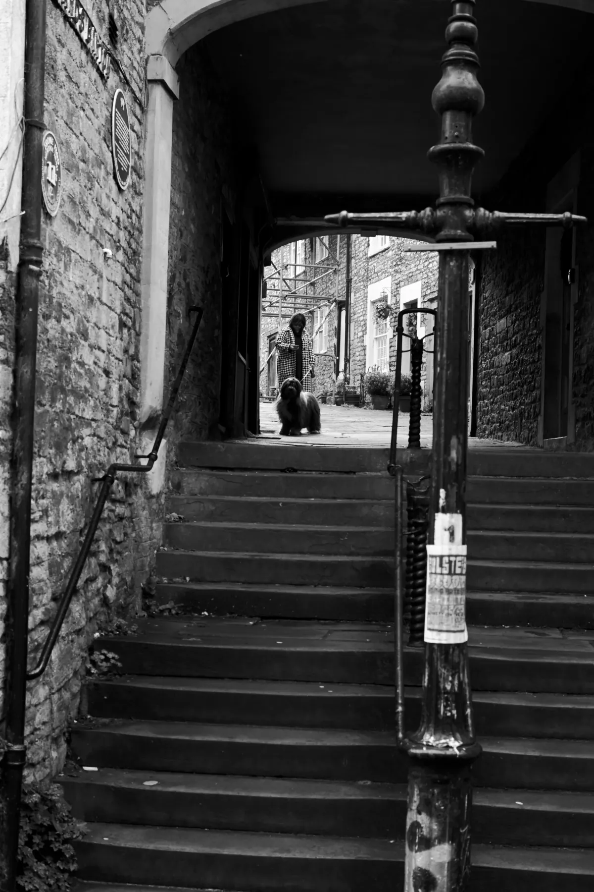 Stone steps leading up under an archway, with a lamp post in the foreground. Black and white.