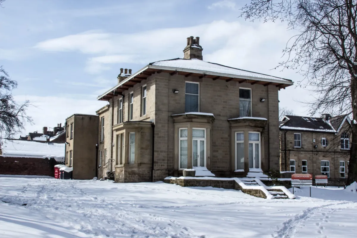 A detached stone Victorian building in the snow.