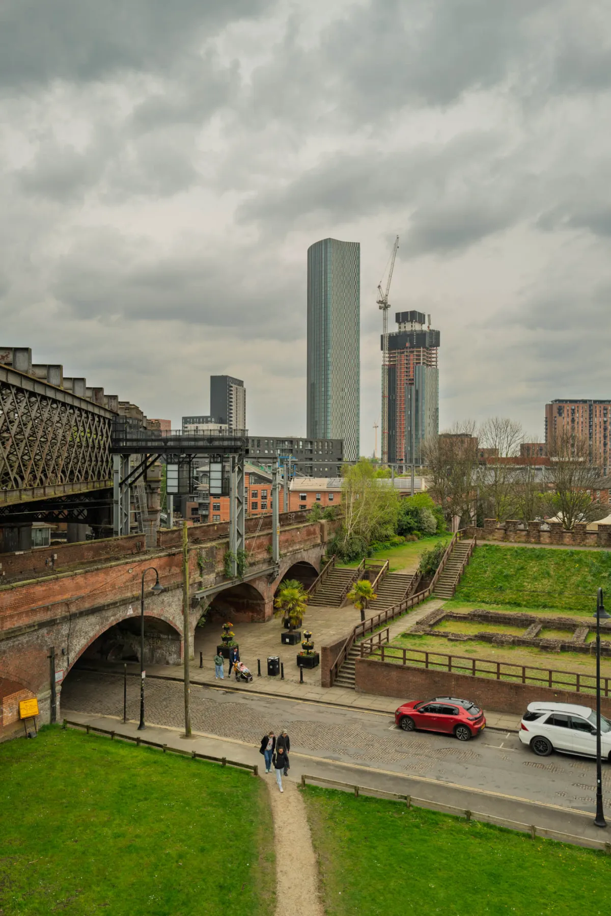 A brick railway viaduct with the Deansgate towers rising behind.