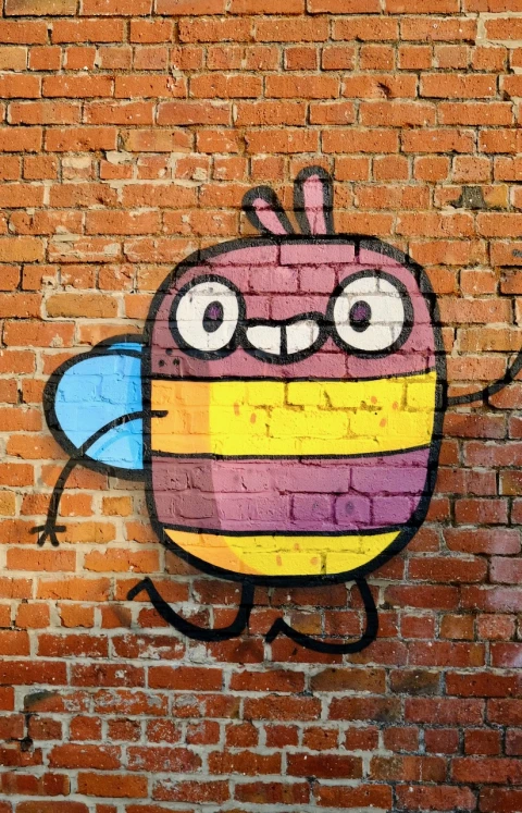 A cartoon bee character painted on a red brick wall.