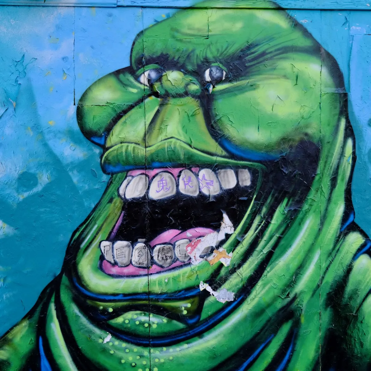 A mural of a green cartoon monster smoking a cigarette, on a blue background.
