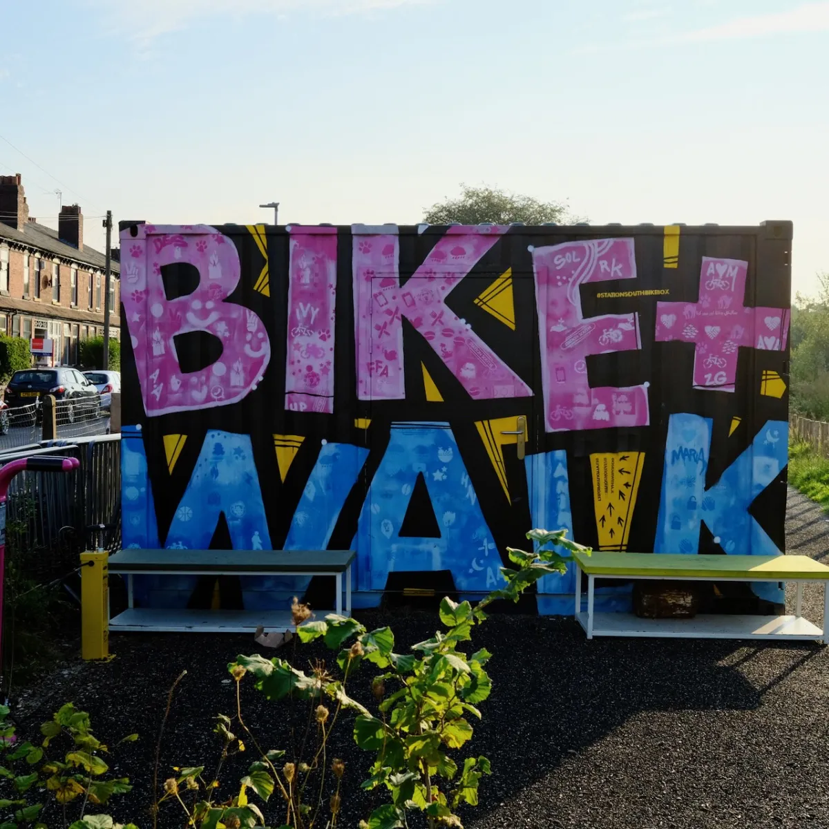 A shipping container painted with the words Bike and Walk in pink and blue.