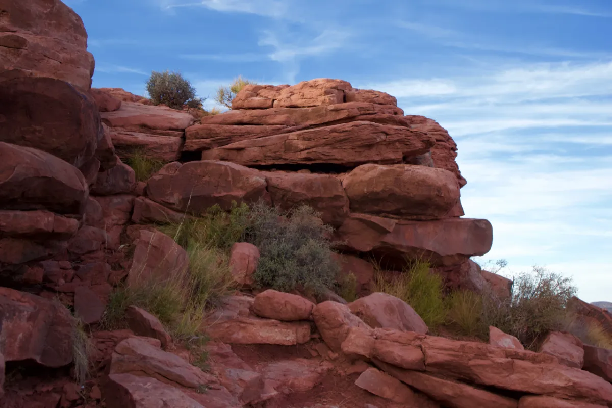 Blocks of red sandstone with scrub growing between them.