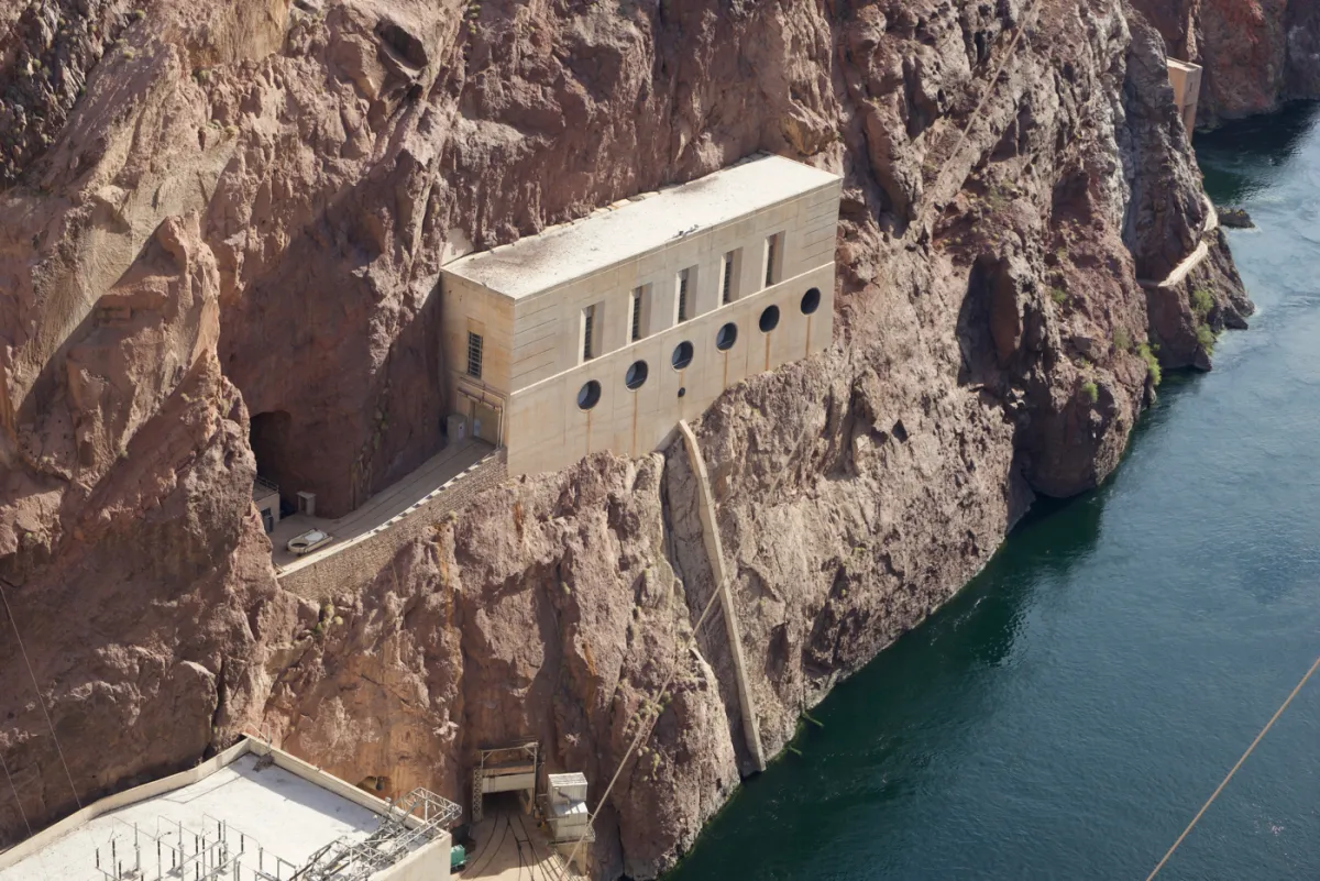 A concrete intake building set into the rock face above the Colorado River.