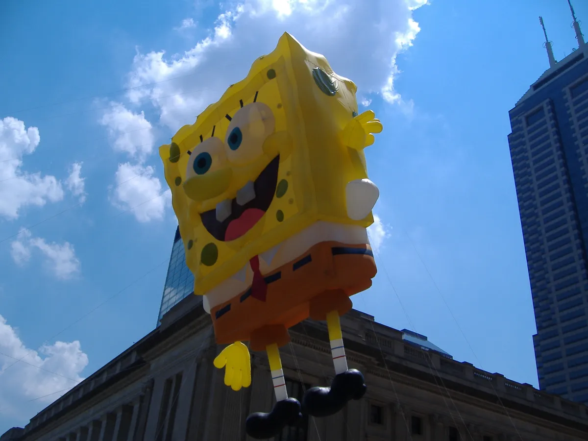 A SpongeBob SquarePants parade balloon seen from below against a blue sky.