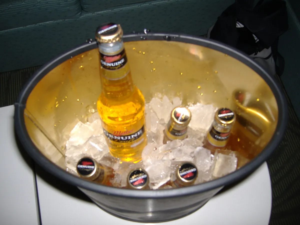 Bottles of beer in a metal bucket of ice.