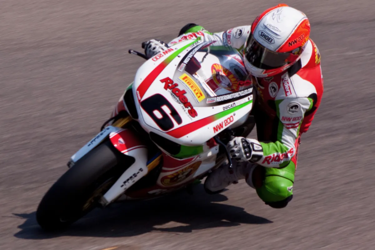 A rider leaning into a corner on a red and white racing motorcycle.