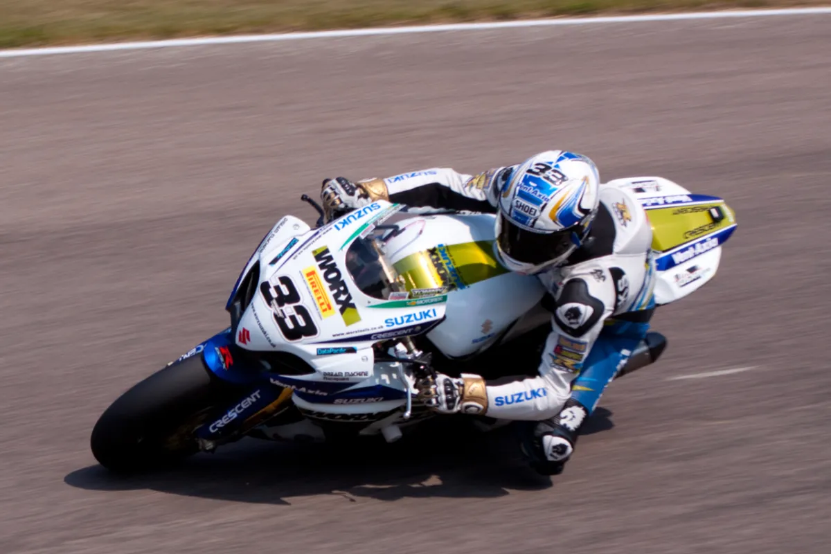 A rider cornering on a white Suzuki racing motorcycle numbered 33.