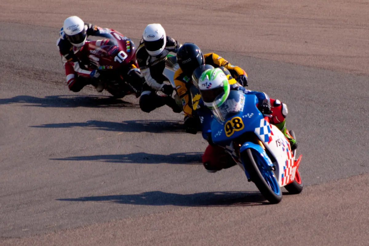 Four racing motorcycles cornering in close formation.