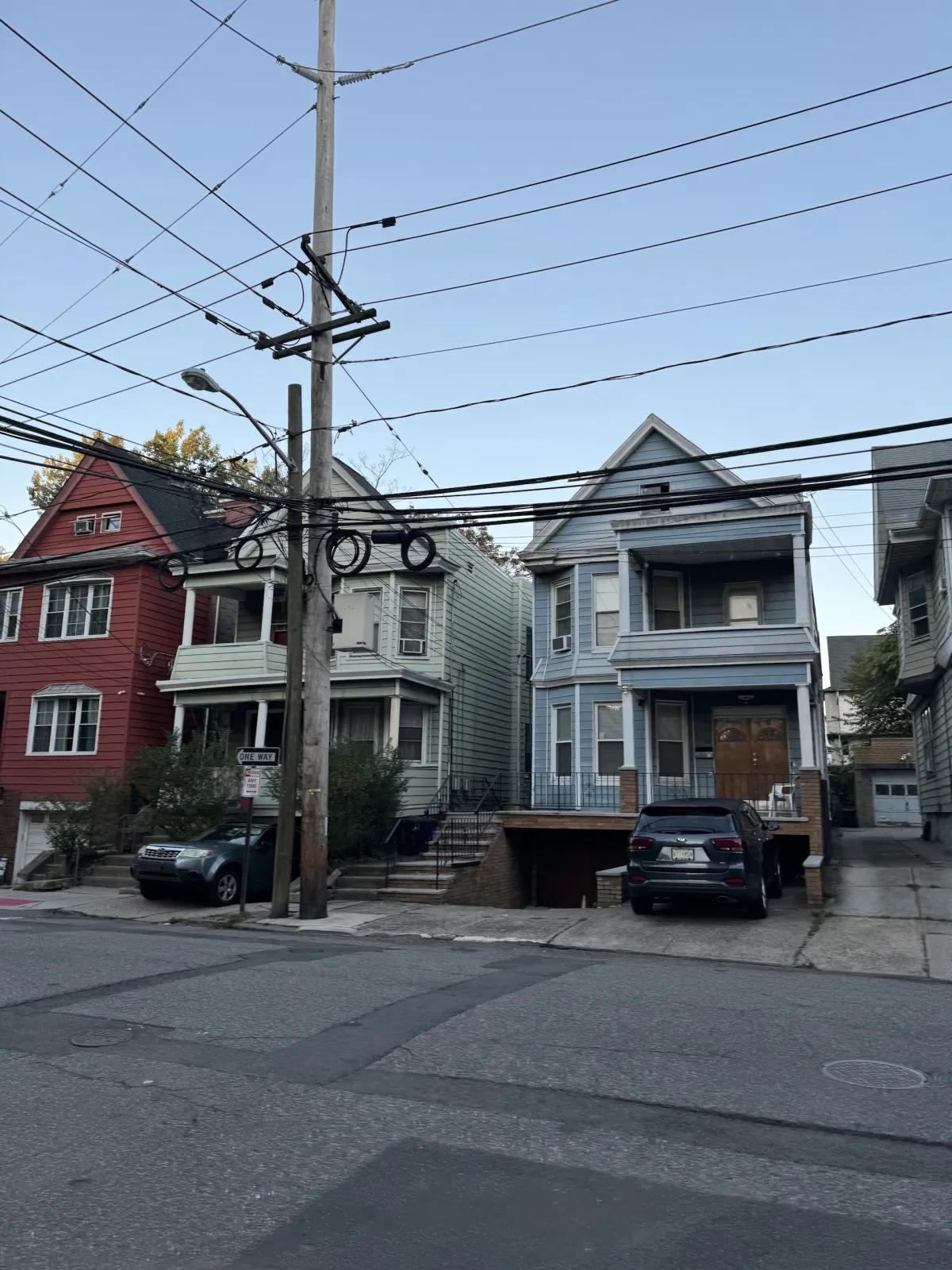 Two clapboard houses on a residential street, with overhead power lines across the frame.