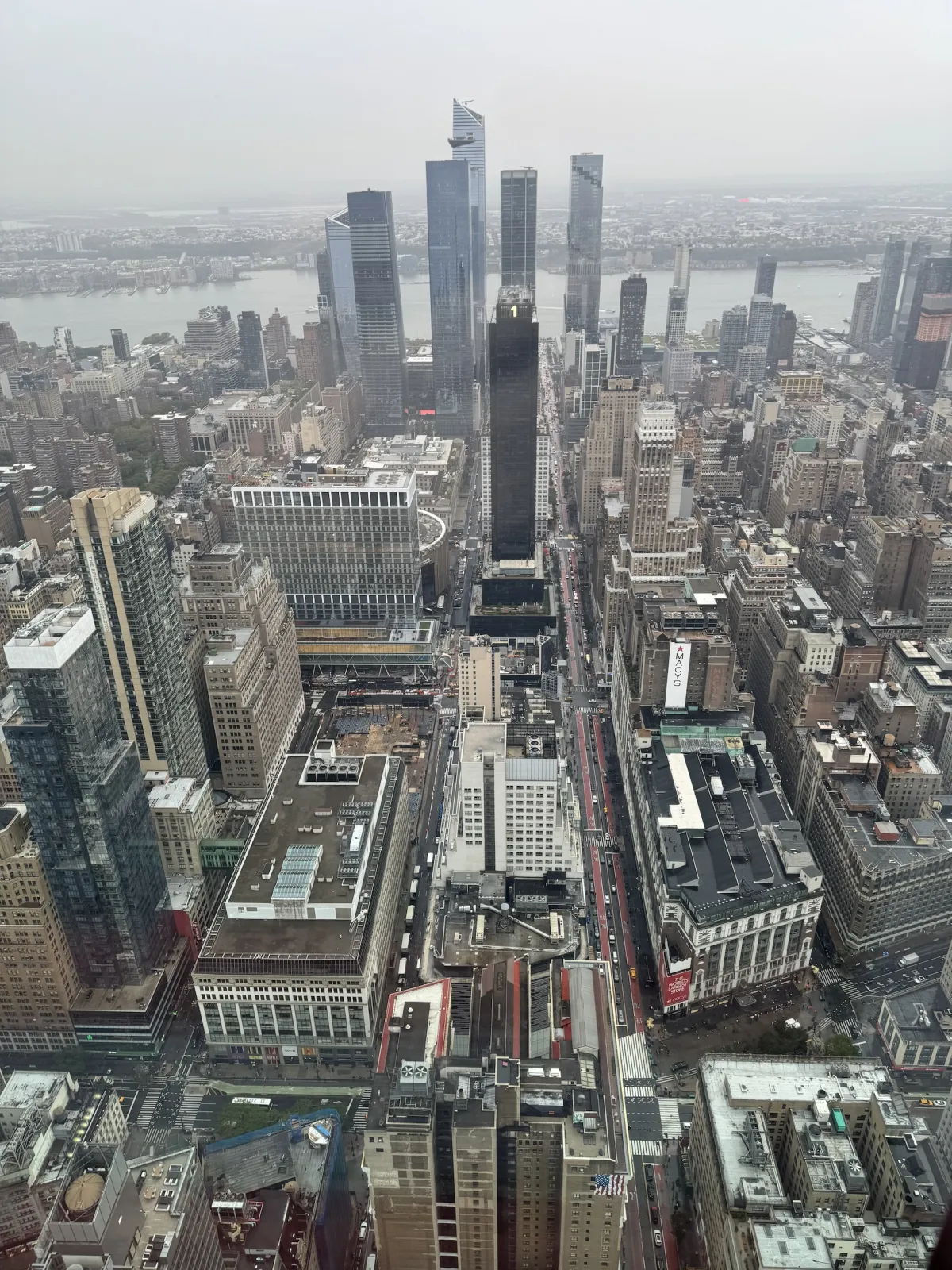 A high view over Manhattan rooftops towards the Hudson Yards towers.