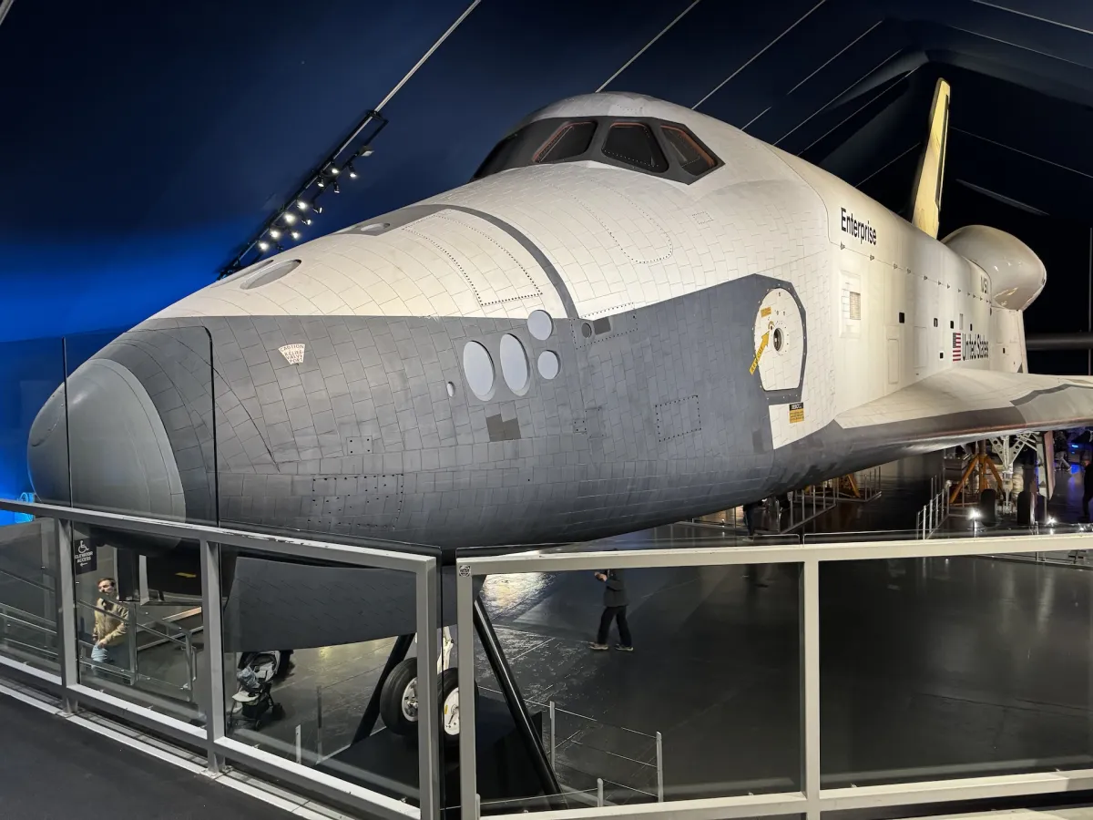 The Space Shuttle Enterprise on display in a darkened hall.