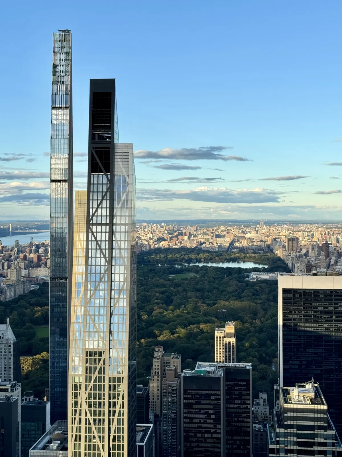 Two slender skyscrapers beside Central Park, seen from above with the park stretching behind.