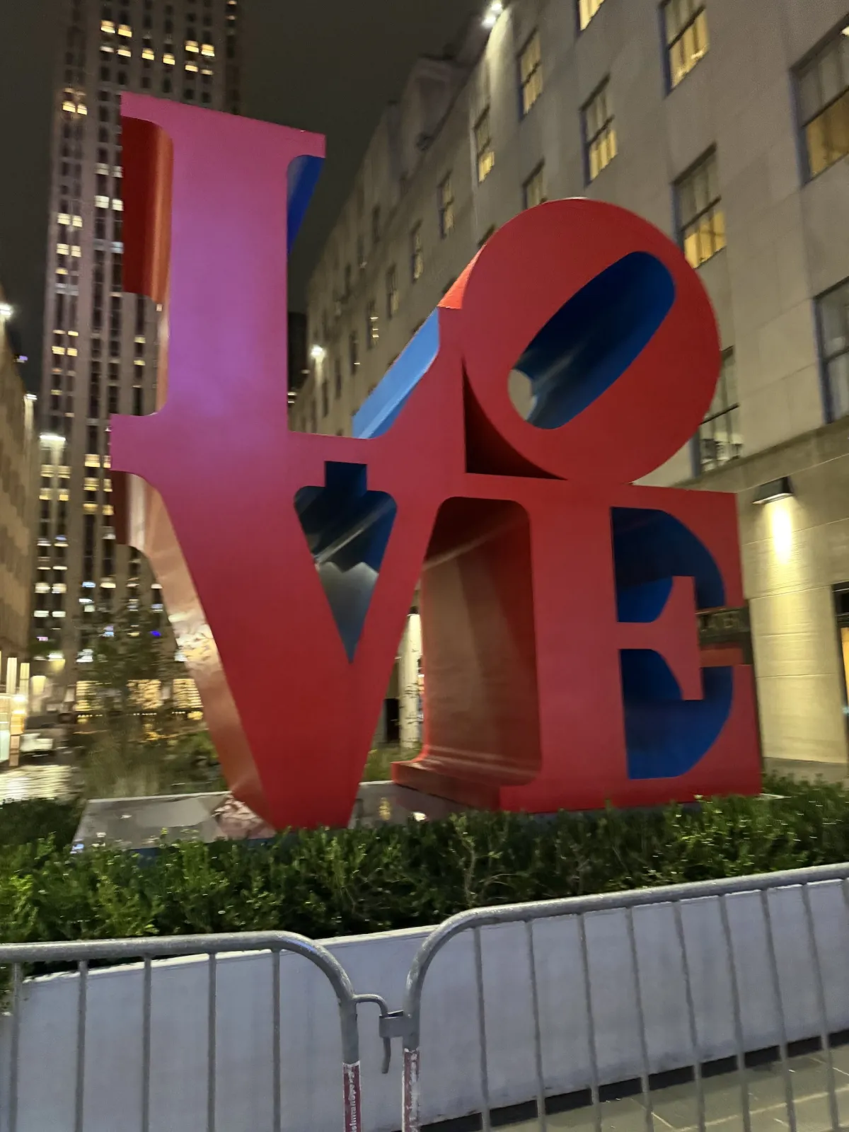 The red and blue LOVE sculpture on a street at night.