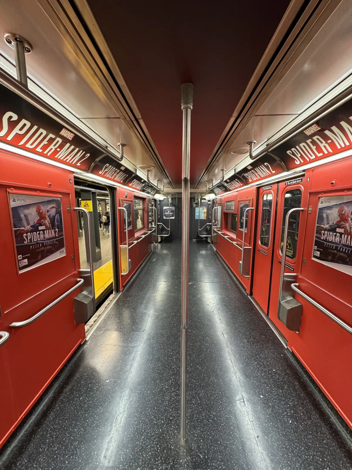 The inside of an empty subway carriage wrapped in red Spider-Man advertising.