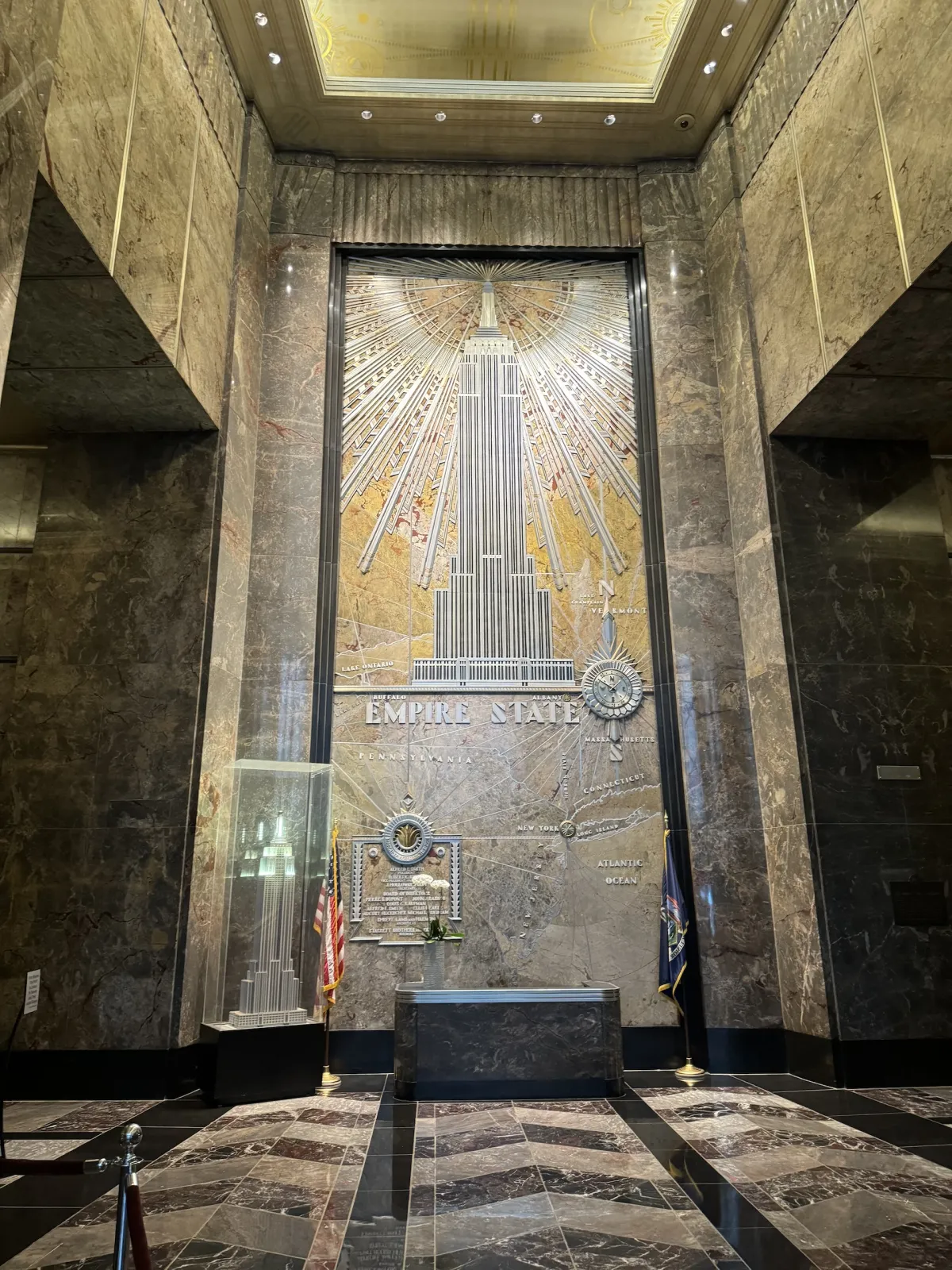 An art deco lobby panel showing the Empire State Building in gold and silver.