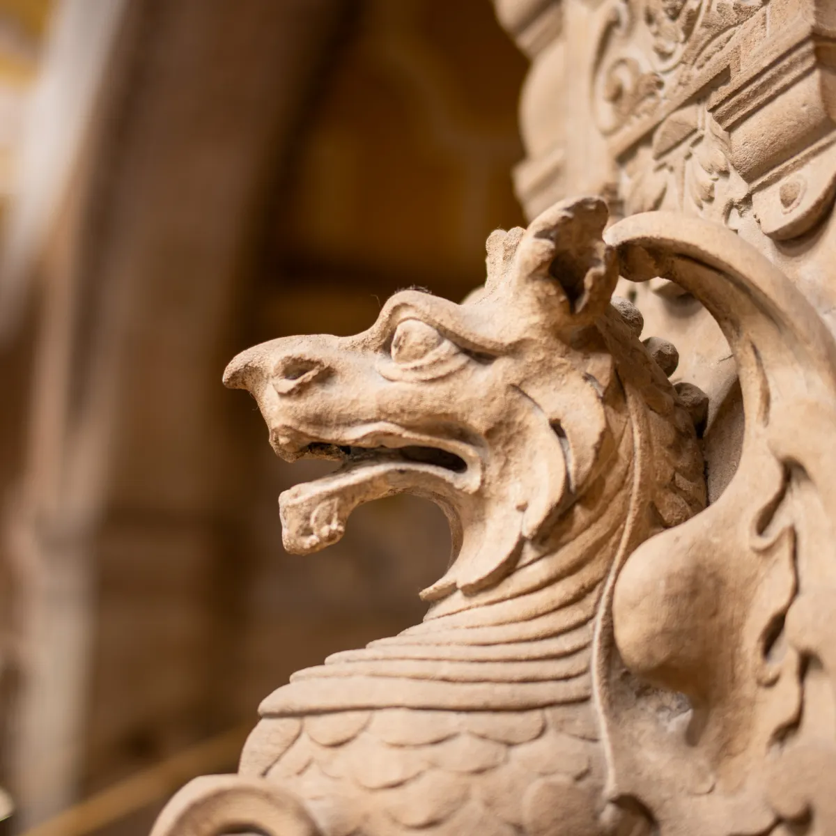 A carved stone dragon's head on the end of a decorated arch.