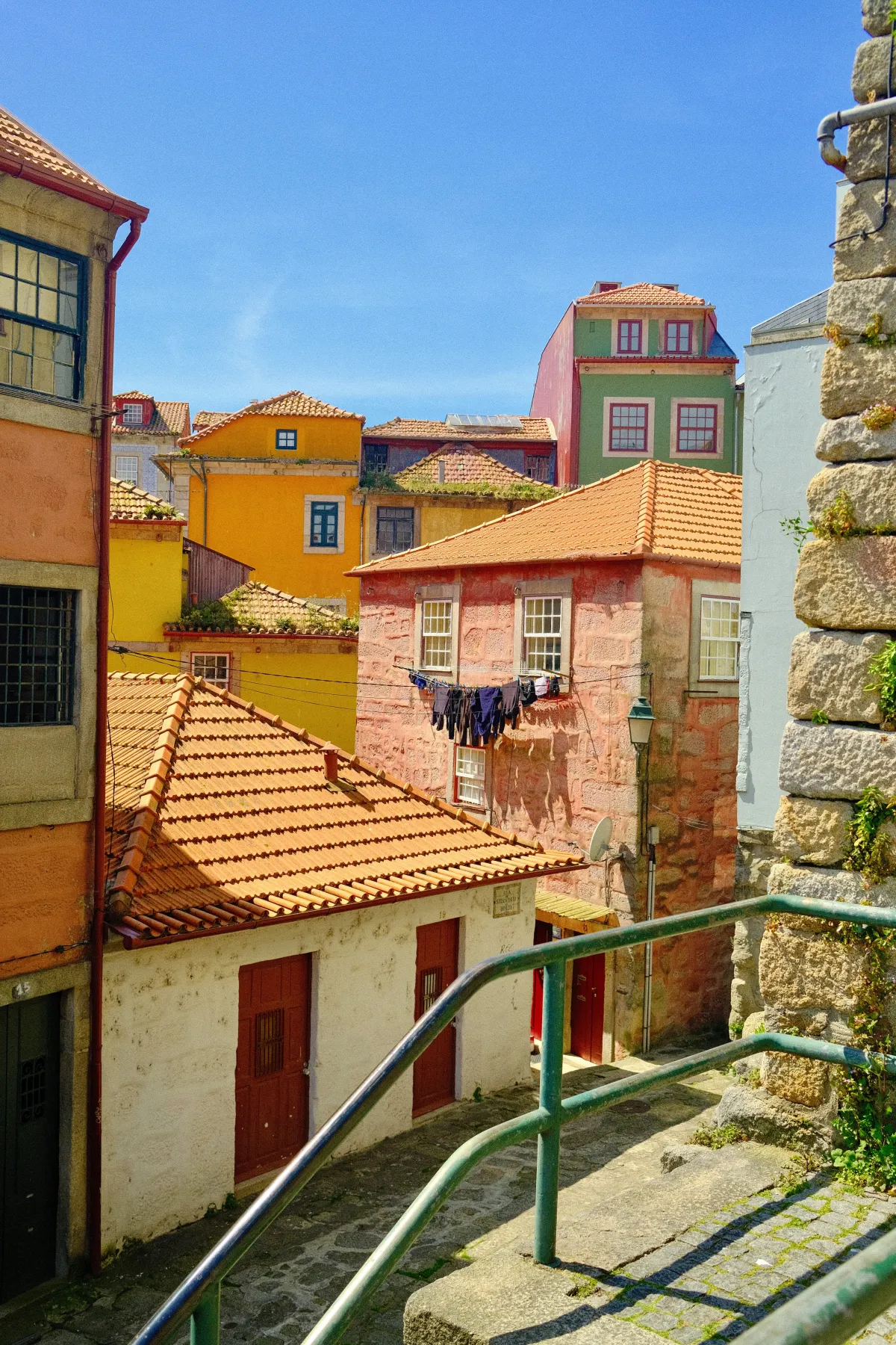 Brightly painted houses stacked above a stepped alleyway, with washing hung out to dry between them.