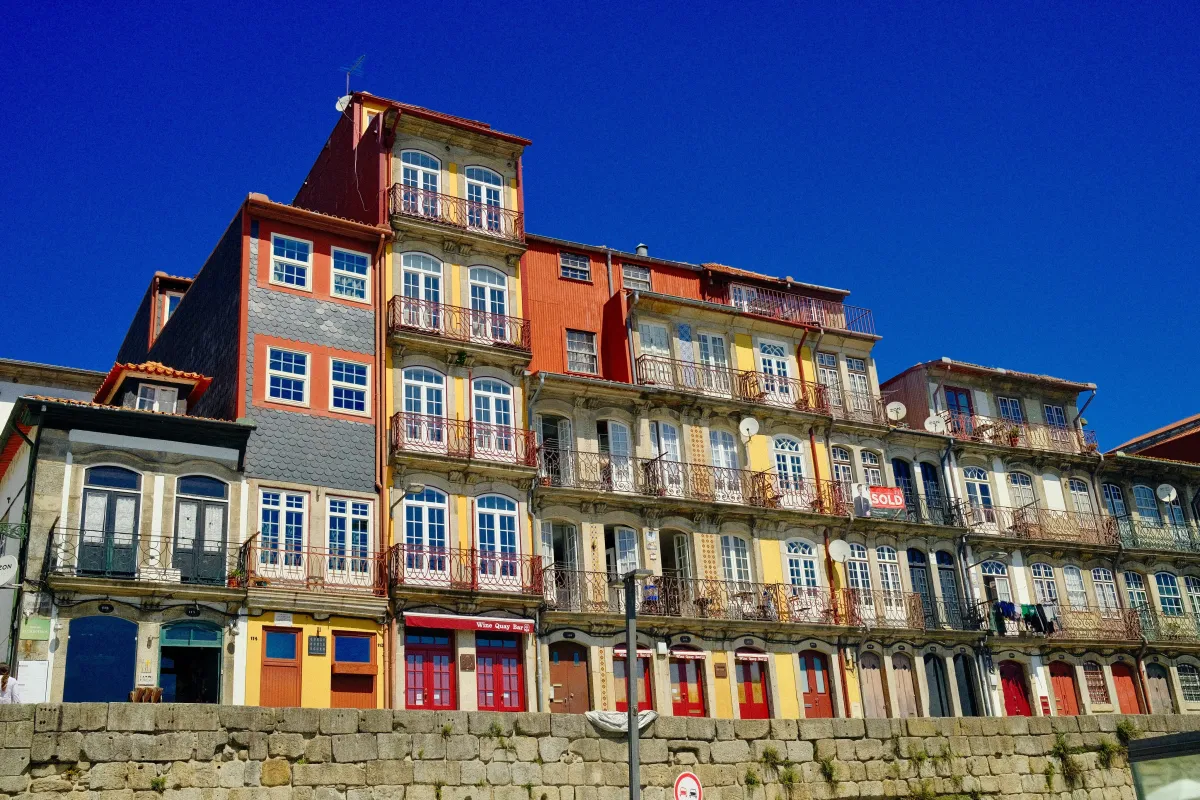 A terrace of tall, narrow houses painted blue, orange and yellow against a deep blue sky.