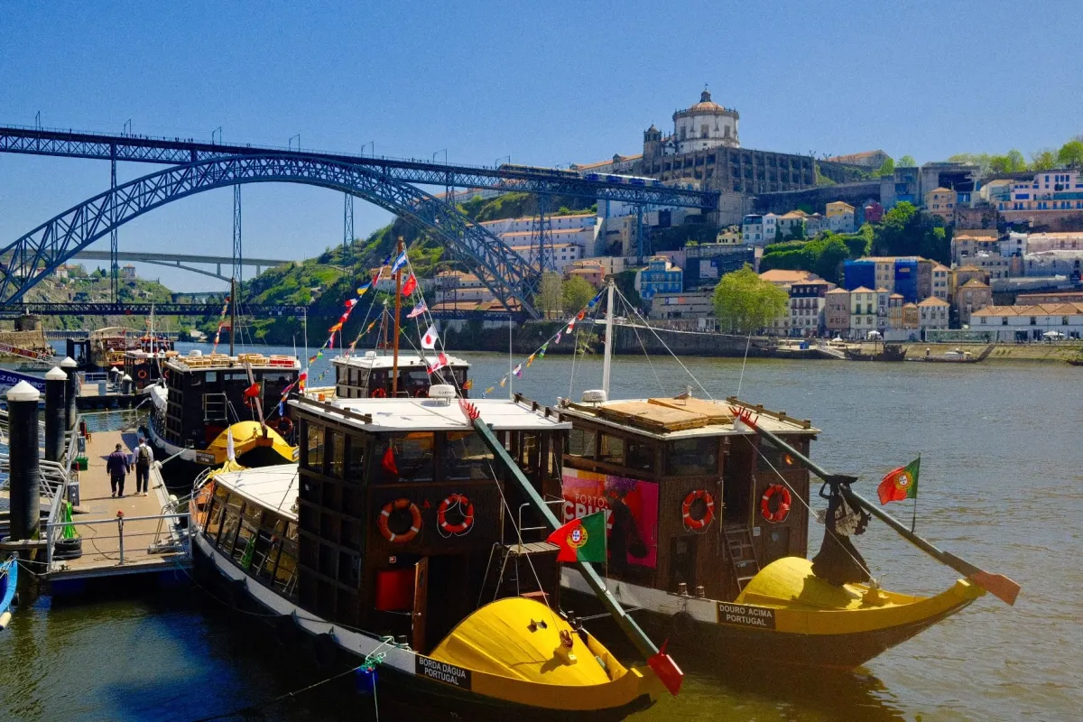 Traditional rabelo boats moored on the Douro beneath the ironwork of the Dom Luís I bridge.