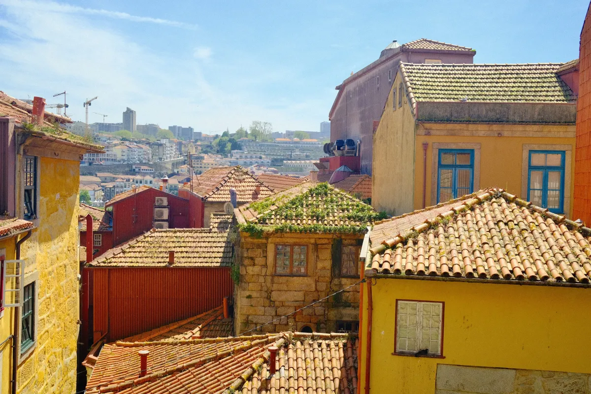 A view across Porto's terracotta rooftops towards the hills, with a construction crane on the skyline.