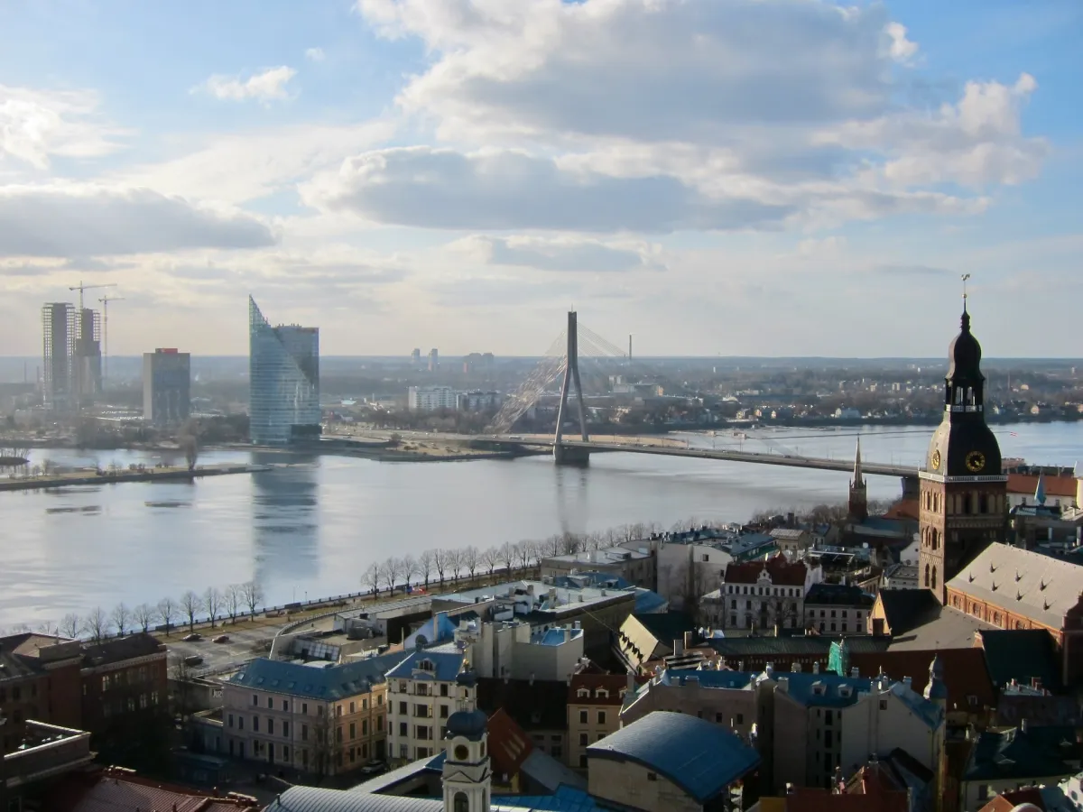 A view over the Daugava river and a cable-stayed bridge, with a church spire in the foreground.