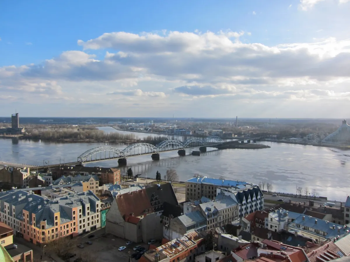 A railway bridge crossing the Daugava, seen from above with the old town in the foreground.