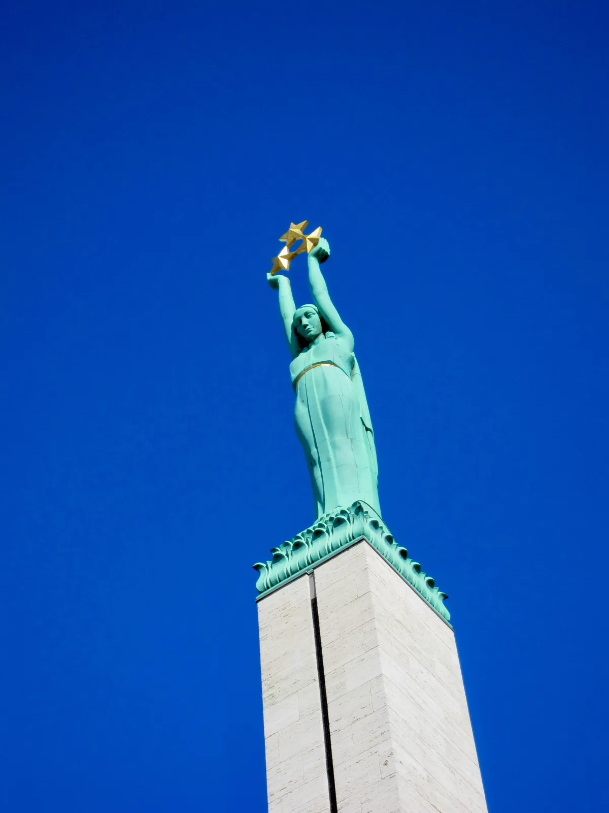The Freedom Monument, a green copper figure holding three stars above a stone column.