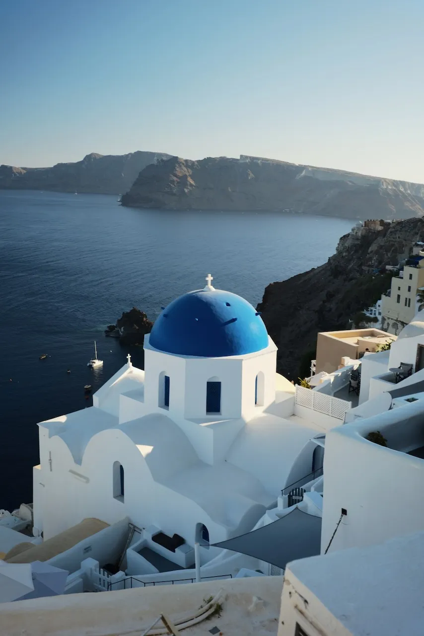 A blue-domed church on the cliff edge, looking out over the caldera.
