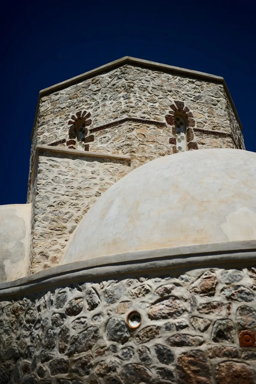 A stone church with a rendered dome, seen from below against a dark blue sky.