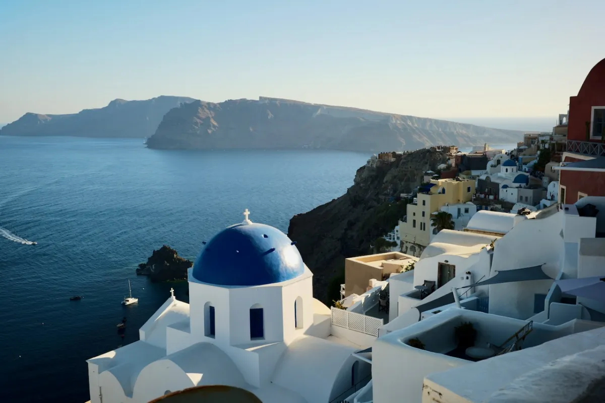 A blue-domed church above the caldera, with whitewashed buildings along the clifftop.