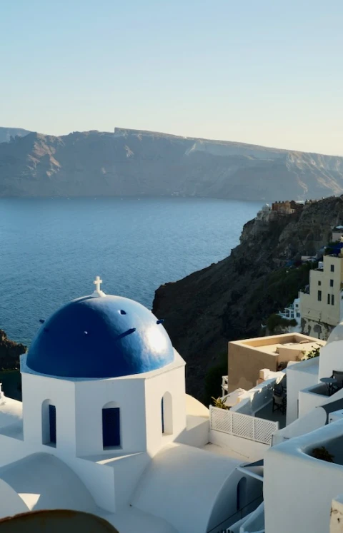 A blue-domed church above the caldera, with whitewashed buildings along the clifftop.