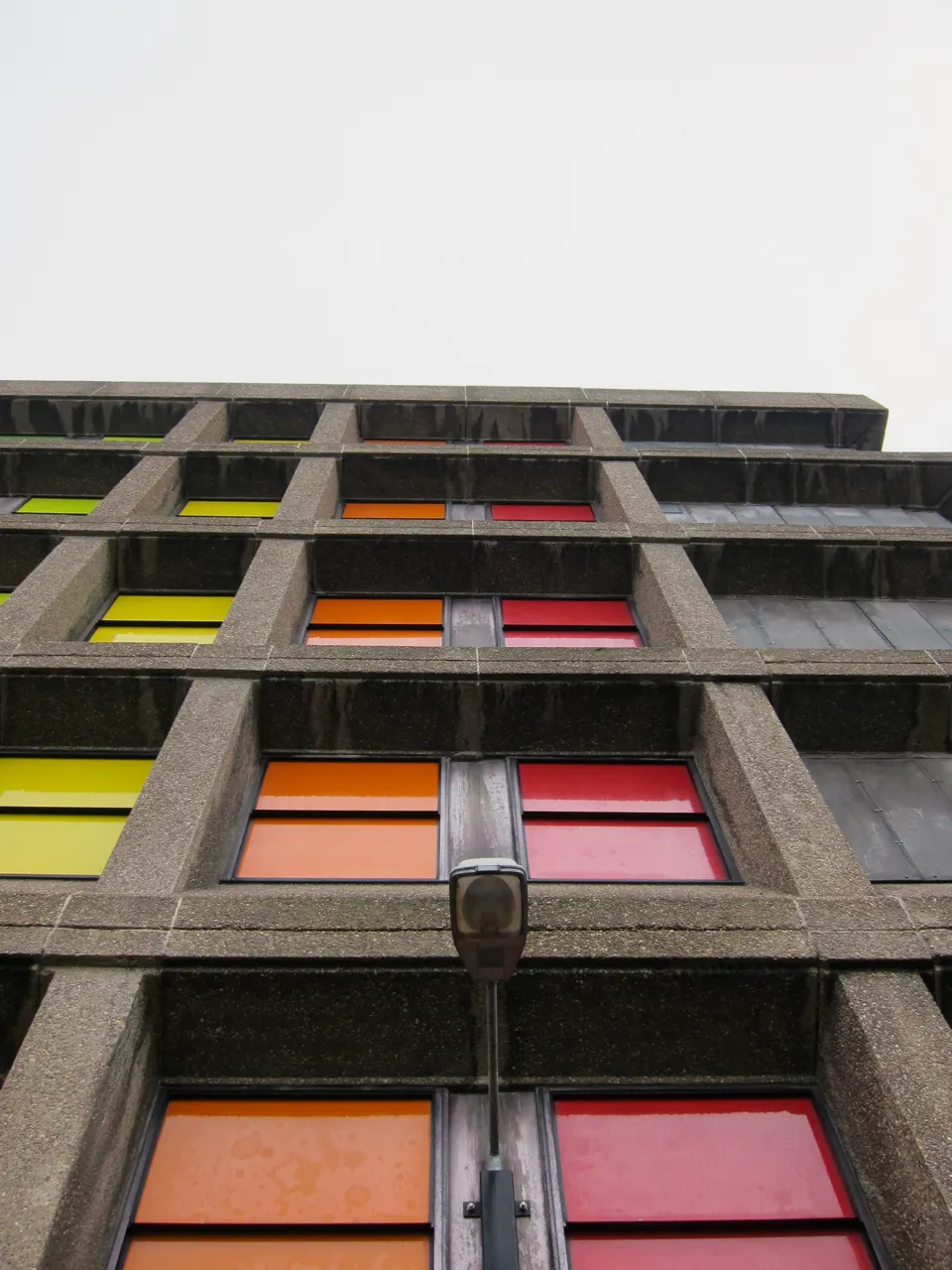 Looking up a concrete facade of red, orange and yellow panels.