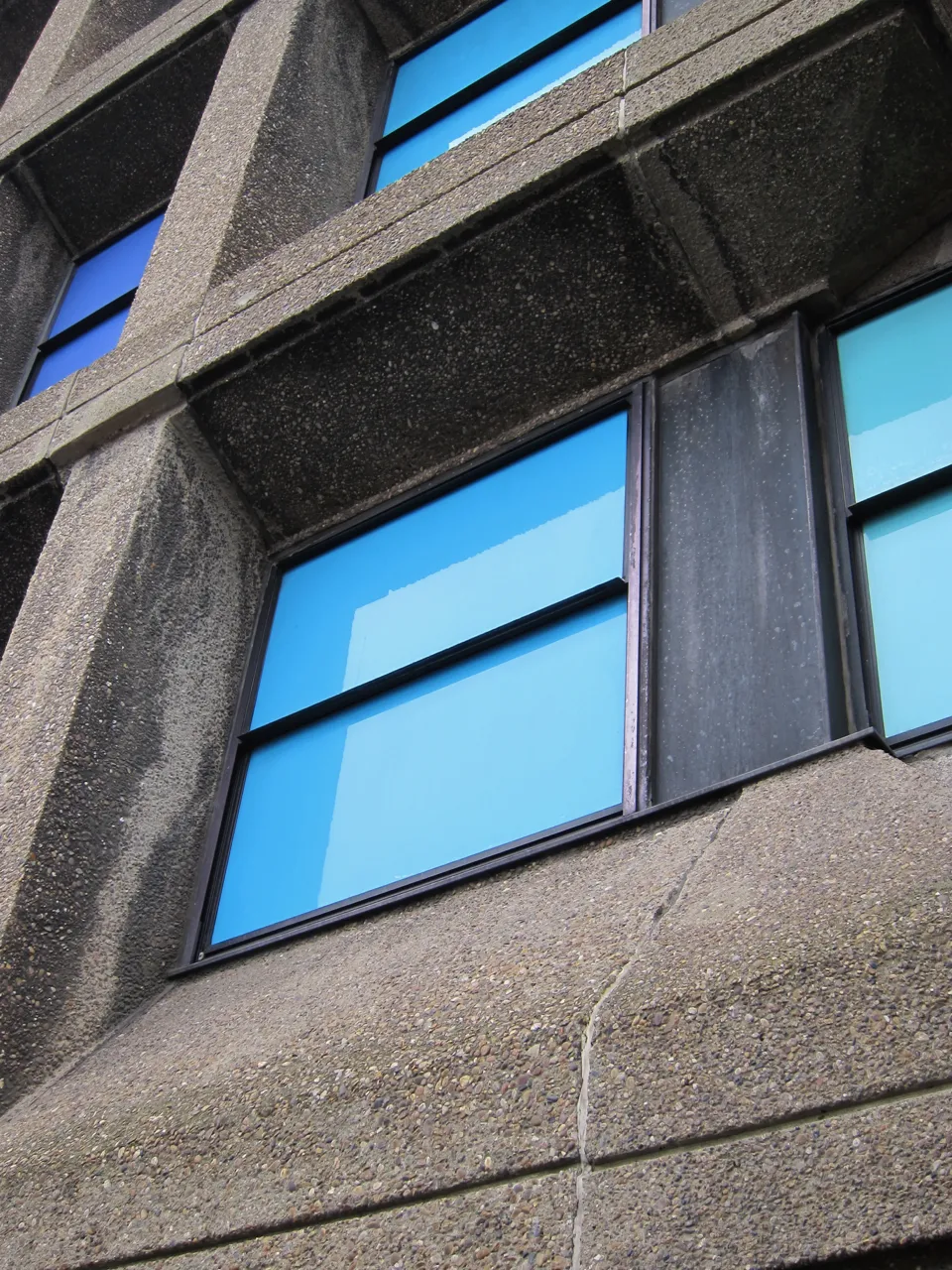 Blue glazed panels set in a weathered concrete frame, seen at an angle.