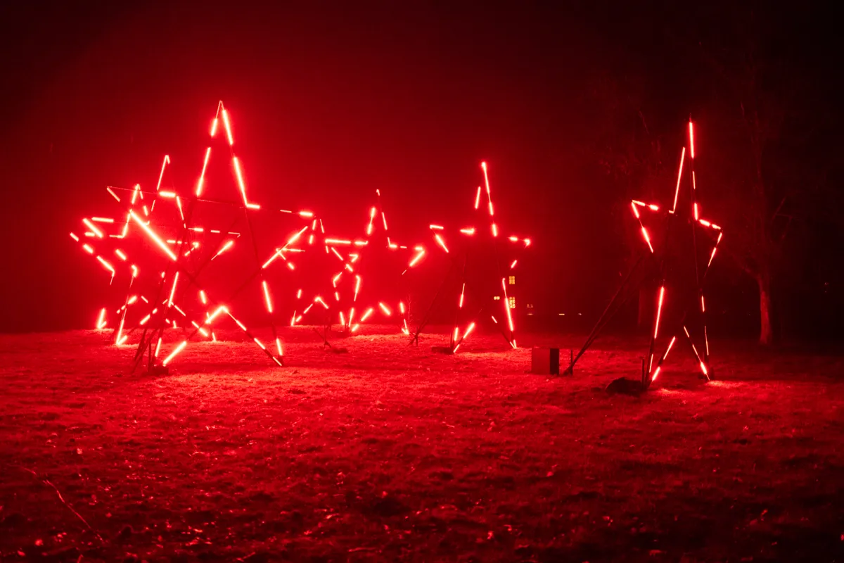Illuminated star frames lit in red on a lawn at night.