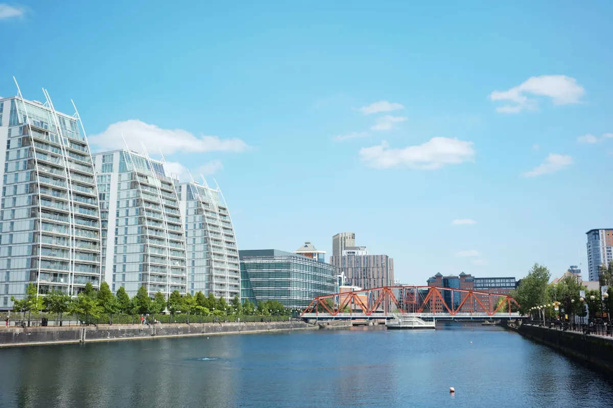 Apartment blocks along a quayside, with a red lift bridge in the distance.