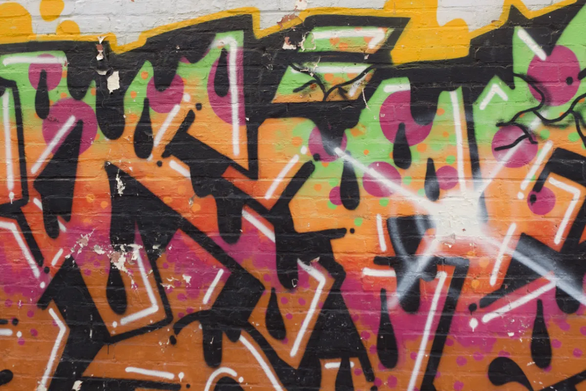 Graffiti in pink, green and orange with dripping black outlines.