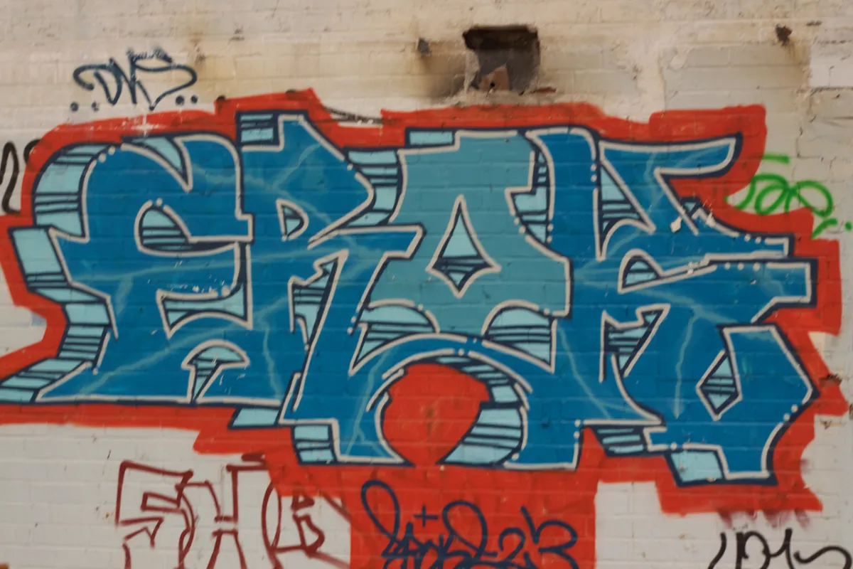 Large blue and red graffiti lettering on a white painted wall.